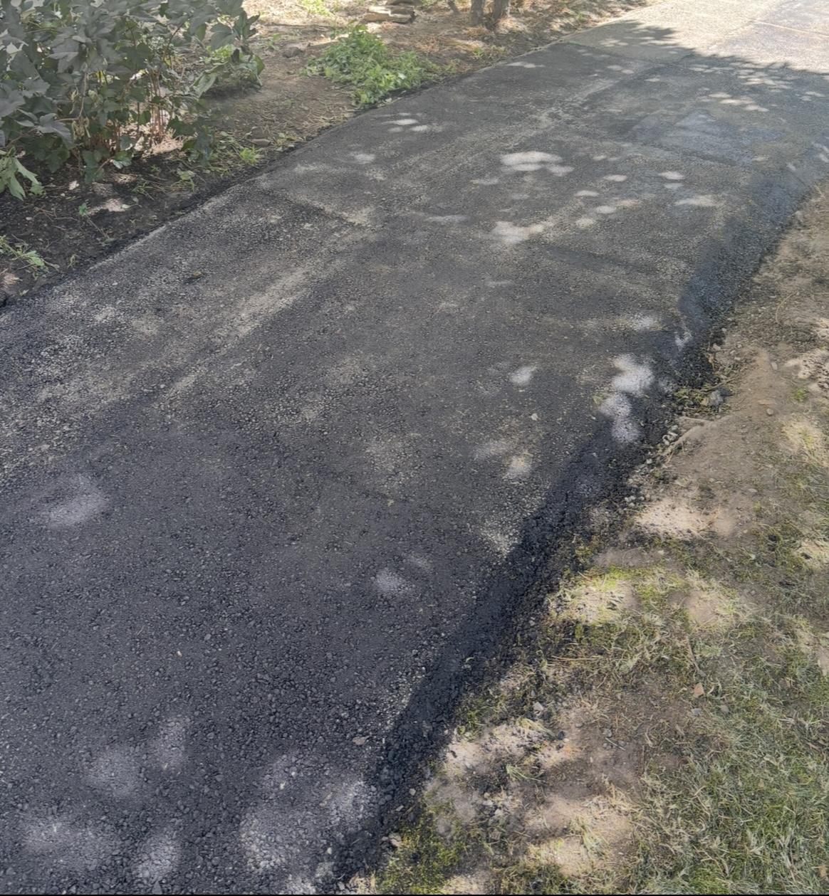 Completed asphalt patch repair beside a landscaped edge in Nanaimo.